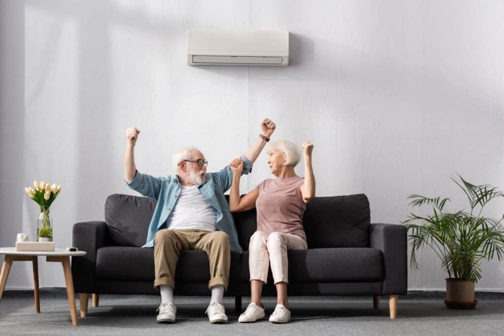 older couple sitting on couch happy with heat pump